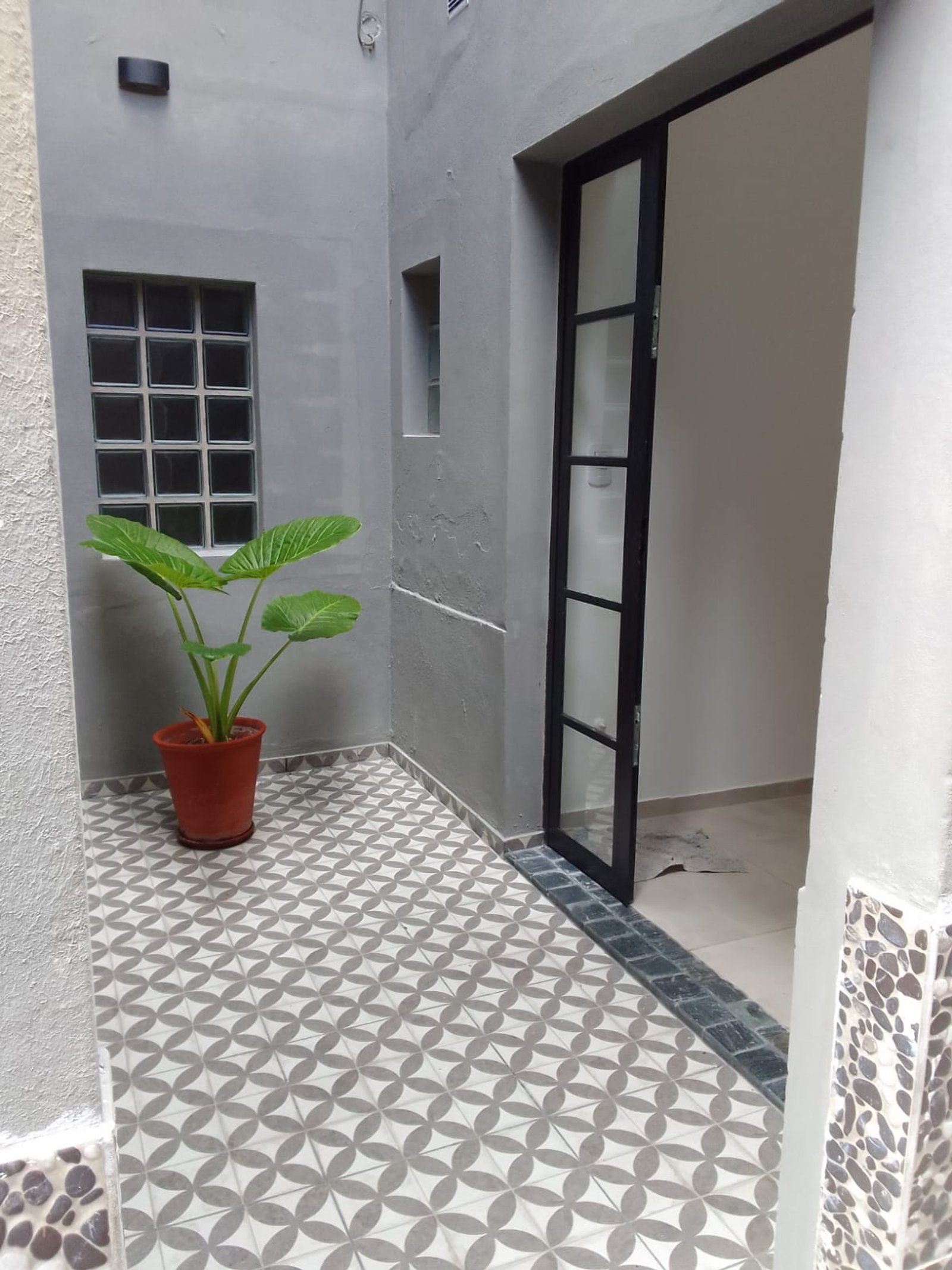 Patio moderno con baldosas geométricas y planta en maceta — proyecto Casa en Sarandi, por Arquitecto Guido Niccoli, en B1872 Sarandí